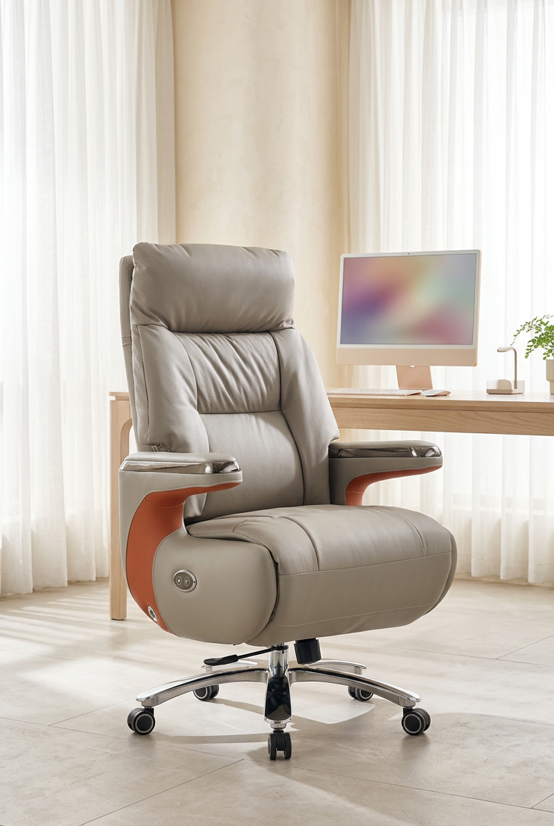 Gray padded high-back office chair with wood-tone arm supports and a wheeled base beside a desk in a sunlit room.