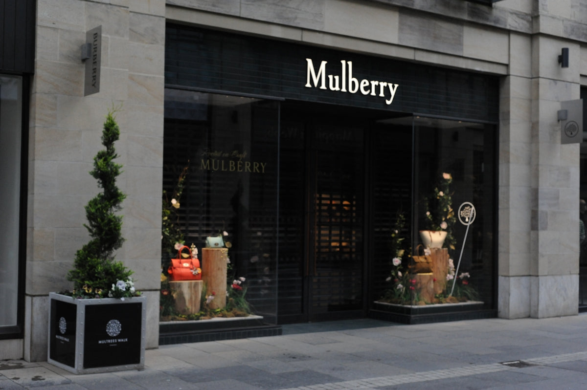 Mulberry luxury store facade with elegant window displays and topiary.