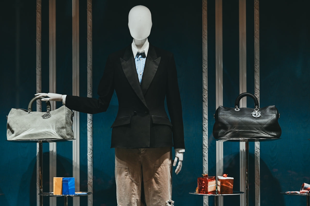Mannequin in tuxedo displaying luxury handbags and gift boxes.