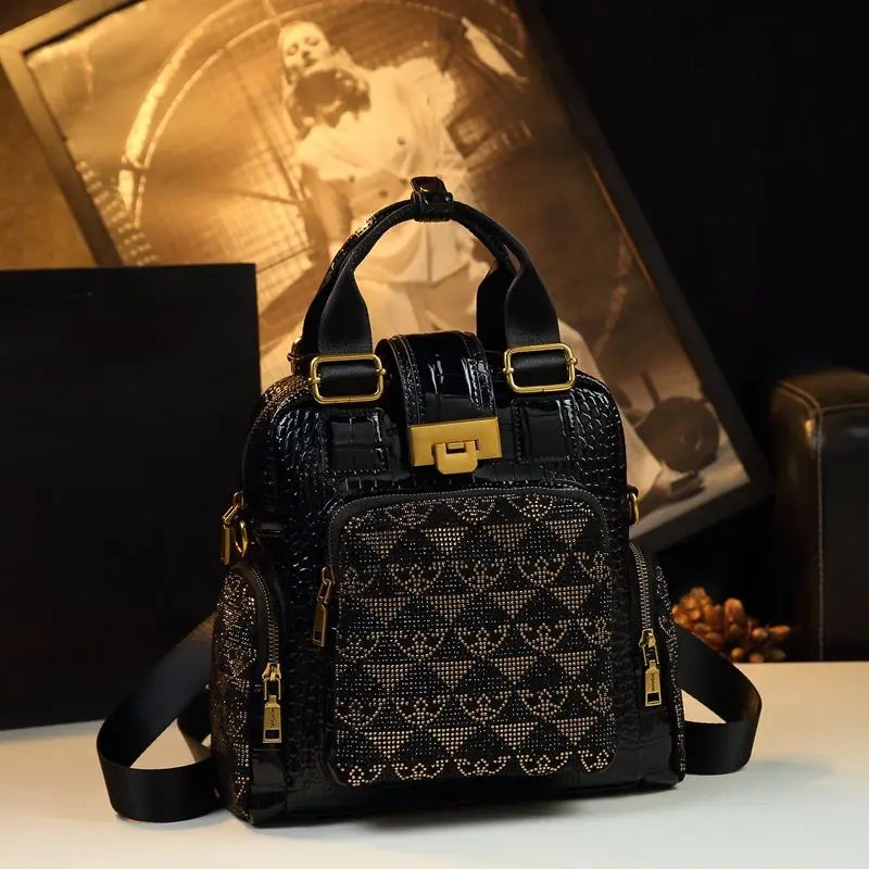 Black patterned handbag with gold accents on a reflective surface