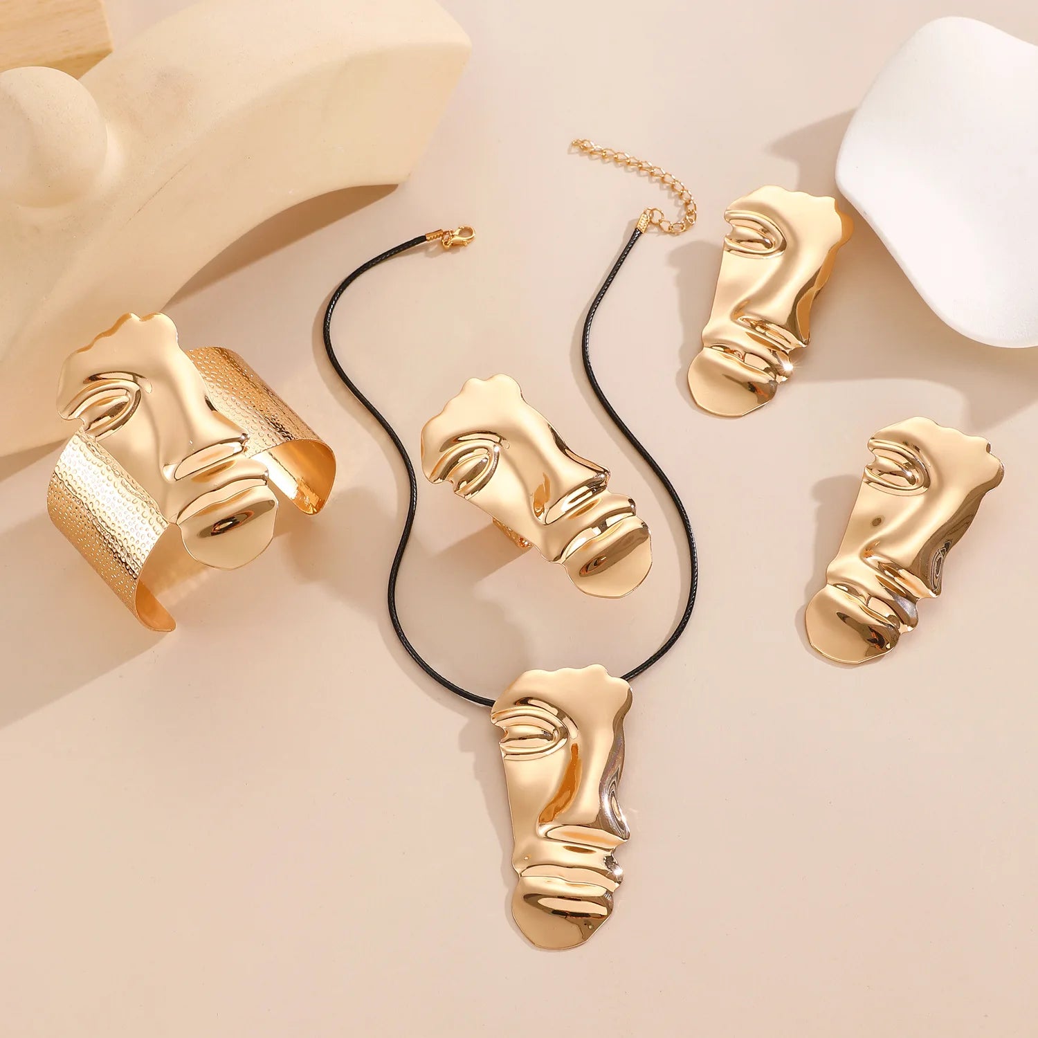 Gold jewelry with face designs on a beige background