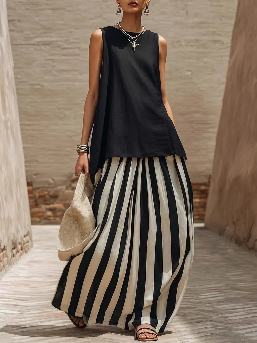 Woman wearing a black sleeveless top and black and white striped pants, holding a beige bag.