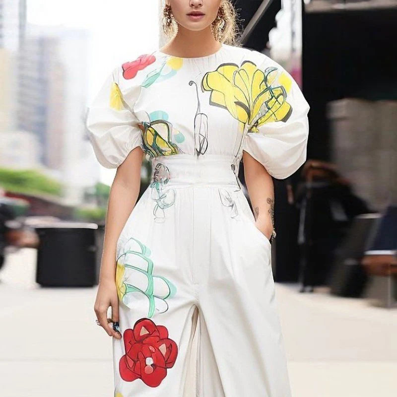 Person wearing a white outfit with colorful floral designs in an urban setting