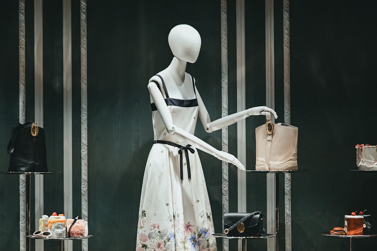 Elegant mannequin in floral dress displaying a handbag.