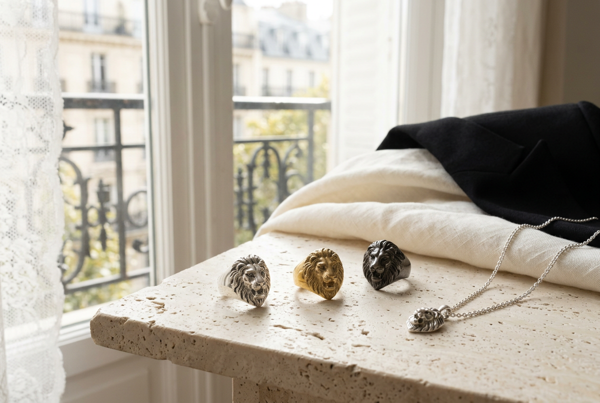 Silver-tone, gold-tone and gunmetal lion-head rings with a lion pendant on sunlit pale stone.