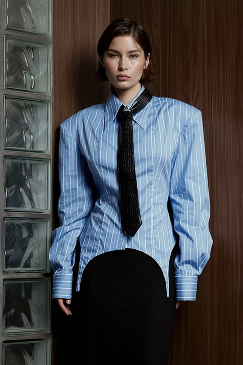 Person wearing a blue striped shirt with a black tie against a wooden wall.