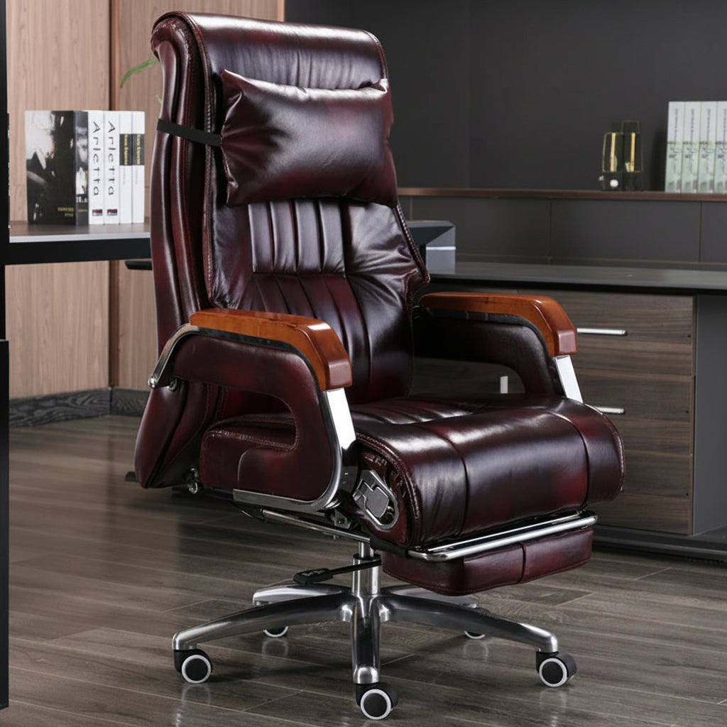 A dark burgundy leather office chair with a matching footrest, shown in a home office setting. The chair features a high back, padded armrests with wood-grain accents, and a chrome five-star wheeled base.