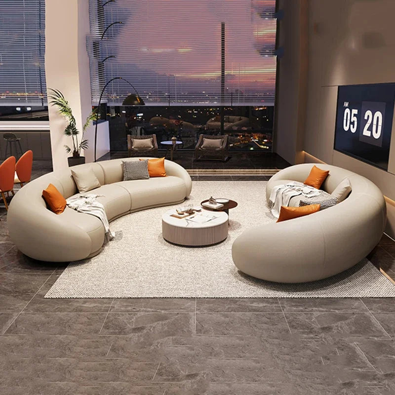 Modern living room with a curved beige sofa, round coffee table, and a large TV.