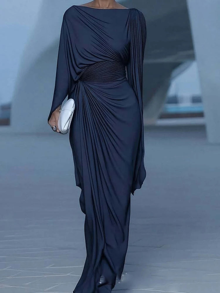 Navy blue draped dress worn by a person in an urban setting