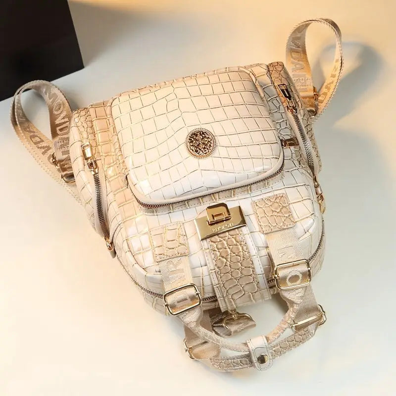 Beige crocodile-patterned backpack on a white surface
