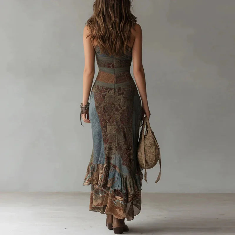 Woman wearing a long, patterned dress holding a bag against a plain background