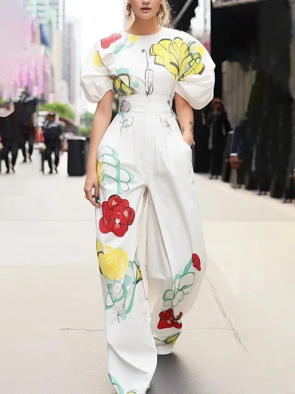 Person wearing a white outfit with colorful floral patterns on a blurred street background