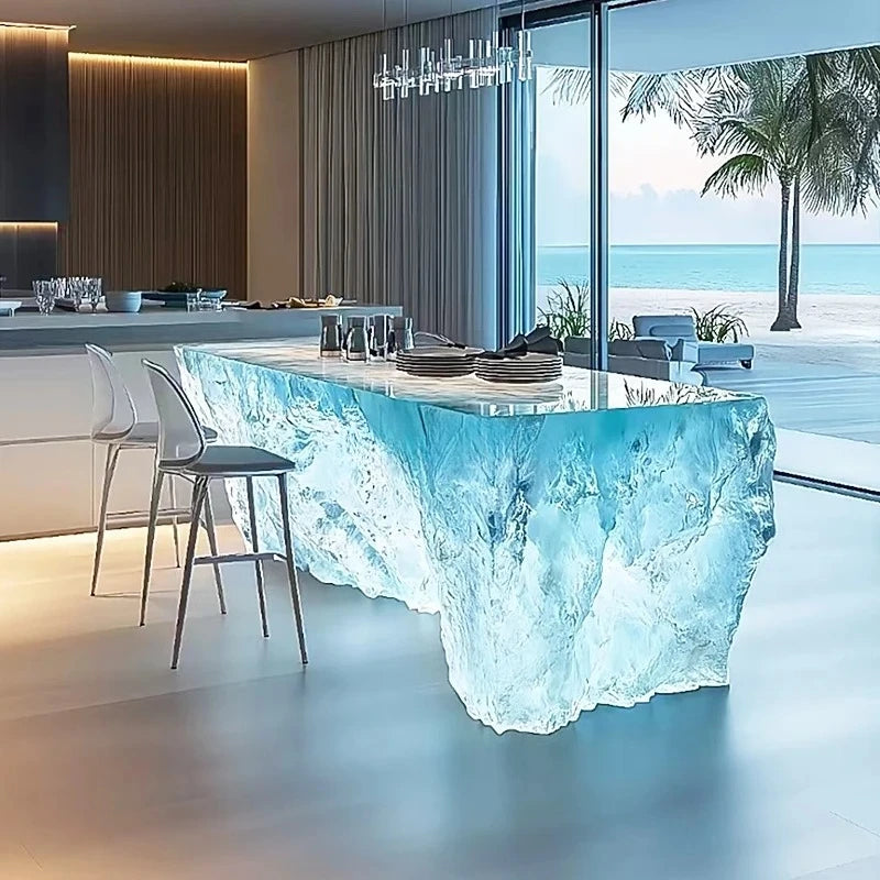 Modern kitchen with a unique table design resembling ocean waves, overlooking a beach.